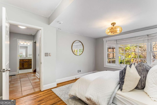 bedroom with ensuite bathroom and hardwood / wood-style floors