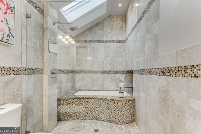 bathroom featuring toilet, lofted ceiling with skylight, tile walls, and a washtub