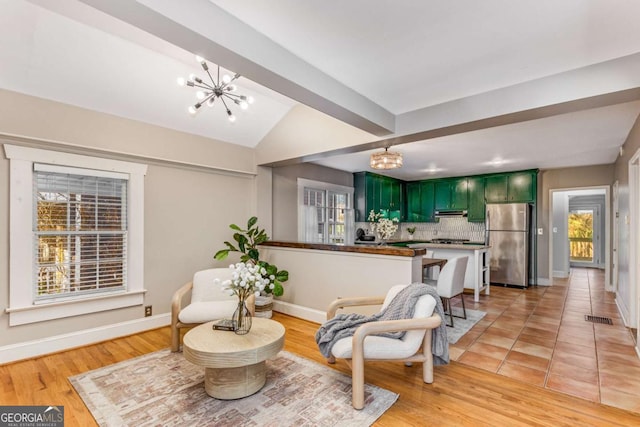 kitchen with stainless steel refrigerator, vaulted ceiling with beams, a notable chandelier, green cabinetry, and kitchen peninsula