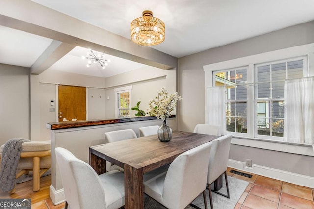 tiled dining room featuring a notable chandelier