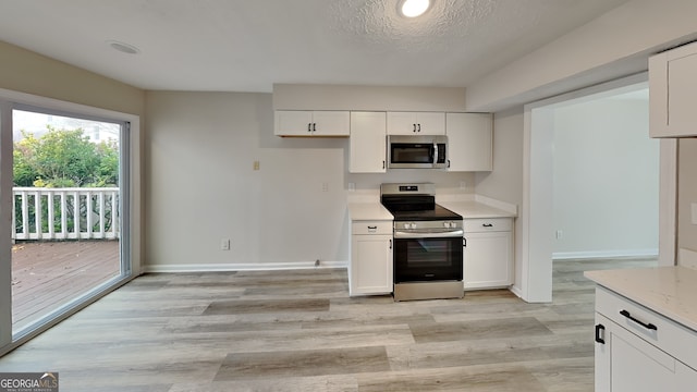 kitchen featuring a textured ceiling, stainless steel appliances, white cabinetry, and light hardwood / wood-style floors