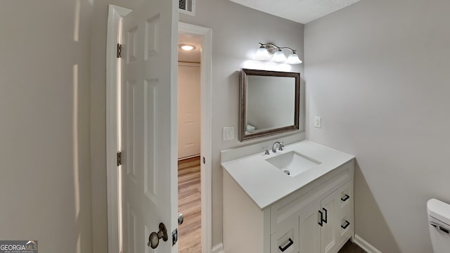 bathroom with hardwood / wood-style floors, vanity, toilet, and a textured ceiling