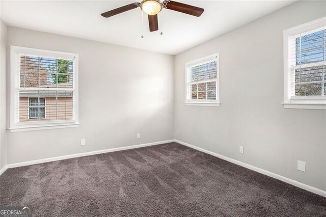 spare room with dark carpet and ceiling fan