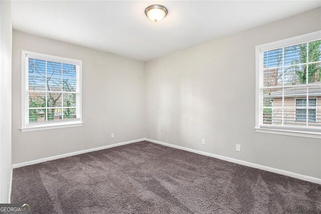 empty room with dark carpet and a healthy amount of sunlight