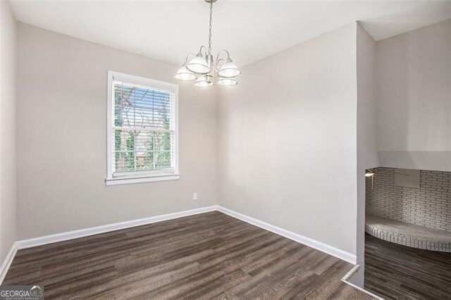 spare room with dark wood-type flooring and a notable chandelier