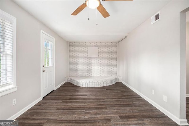 empty room featuring ceiling fan, plenty of natural light, and dark hardwood / wood-style floors