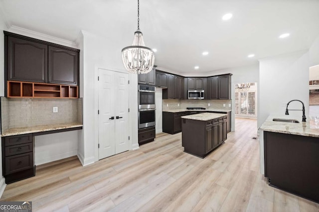 kitchen featuring sink, light hardwood / wood-style floors, pendant lighting, dark brown cabinets, and appliances with stainless steel finishes