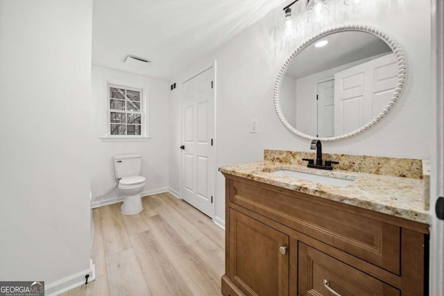 bathroom with hardwood / wood-style floors, vanity, and toilet