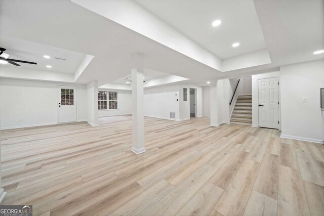 interior space with a raised ceiling, ceiling fan, and light wood-type flooring