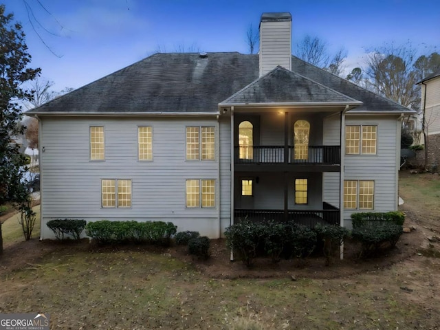 back house at dusk featuring a balcony