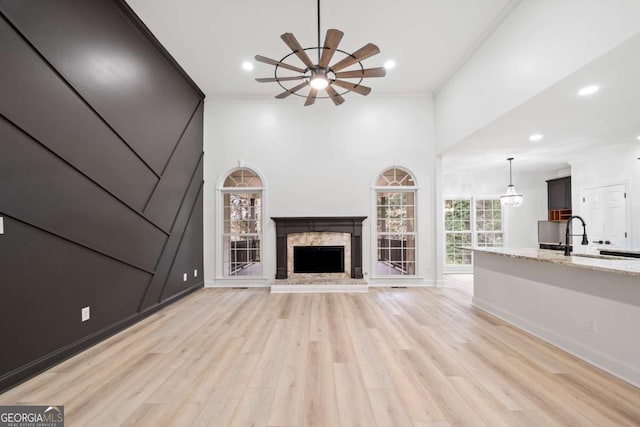 unfurnished living room with ornamental molding, sink, a high end fireplace, and light hardwood / wood-style flooring