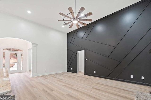 unfurnished room with light wood-type flooring, ornate columns, ceiling fan, and ornamental molding