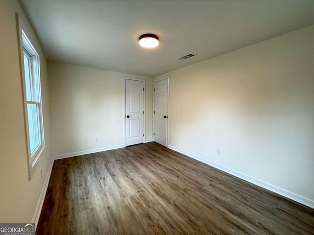 spare room with dark hardwood / wood-style flooring and plenty of natural light