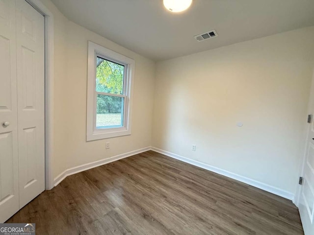 unfurnished bedroom with dark hardwood / wood-style floors and a closet