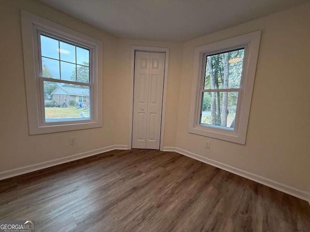 unfurnished bedroom featuring a closet, dark hardwood / wood-style floors, and multiple windows