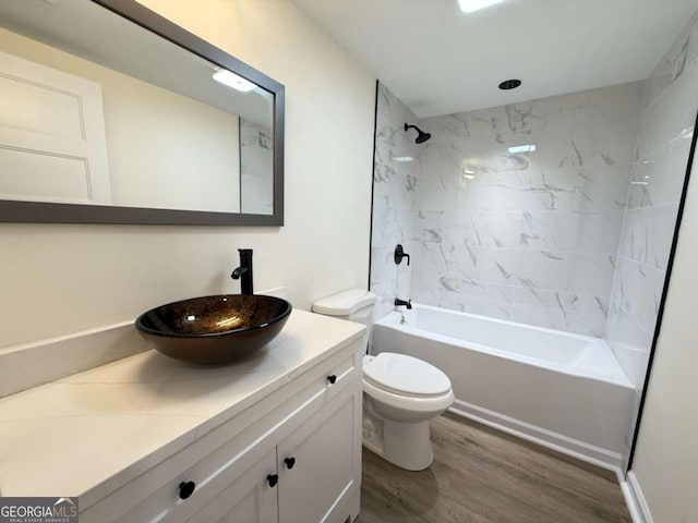 full bathroom featuring hardwood / wood-style floors, tiled shower / bath combo, toilet, and vanity