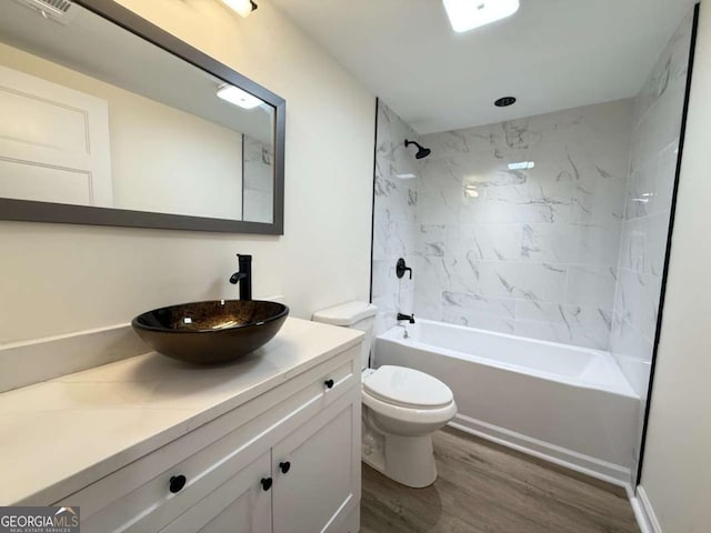 full bathroom with hardwood / wood-style flooring, tiled shower / bath combo, toilet, and vanity