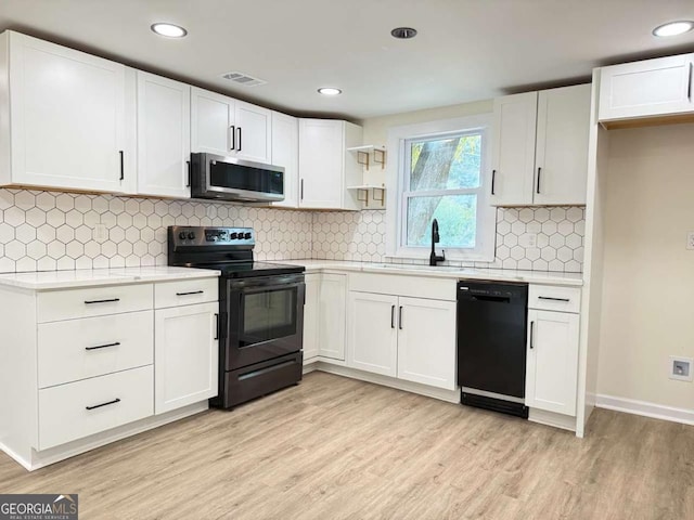 kitchen featuring light wood-type flooring, tasteful backsplash, sink, black appliances, and white cabinets