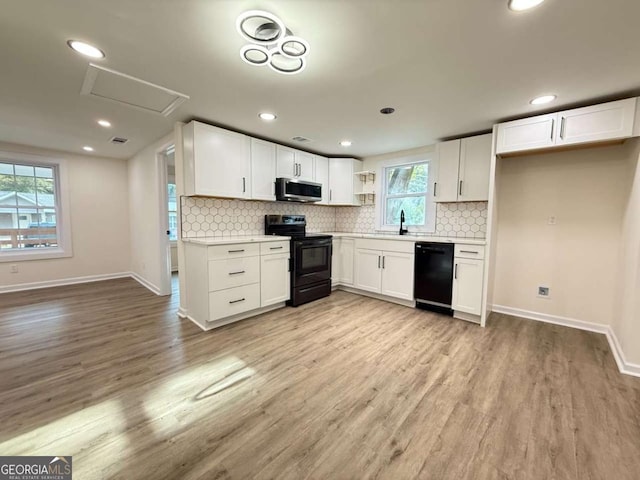 kitchen with black appliances, light wood-type flooring, white cabinetry, and sink