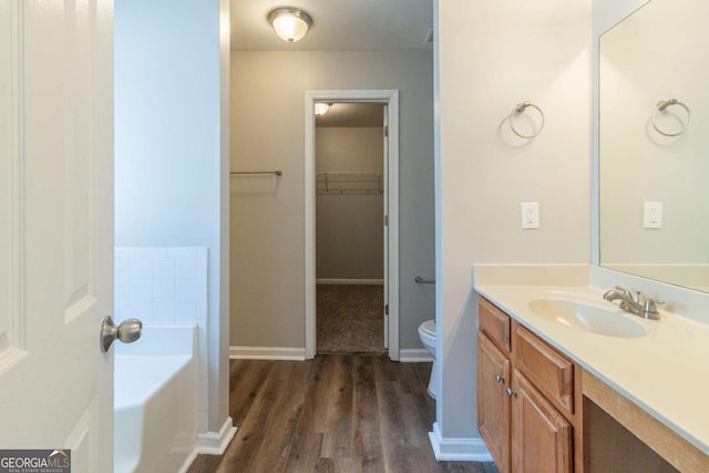 bathroom featuring a bathing tub, vanity, wood-type flooring, and toilet