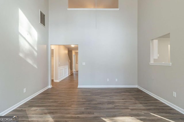 unfurnished room with a high ceiling and dark hardwood / wood-style flooring