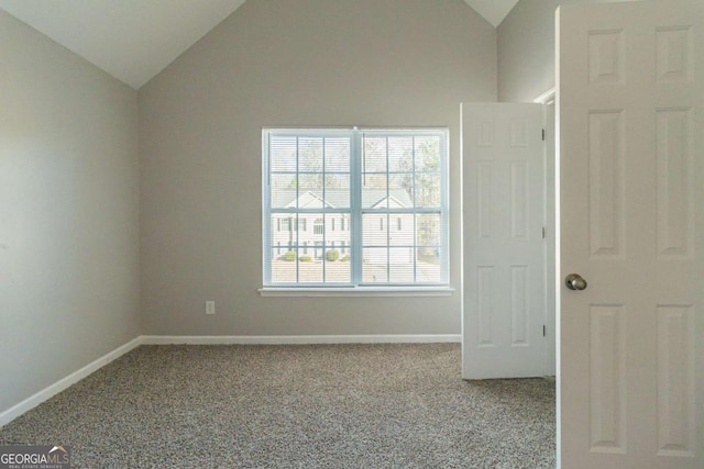 carpeted spare room with vaulted ceiling