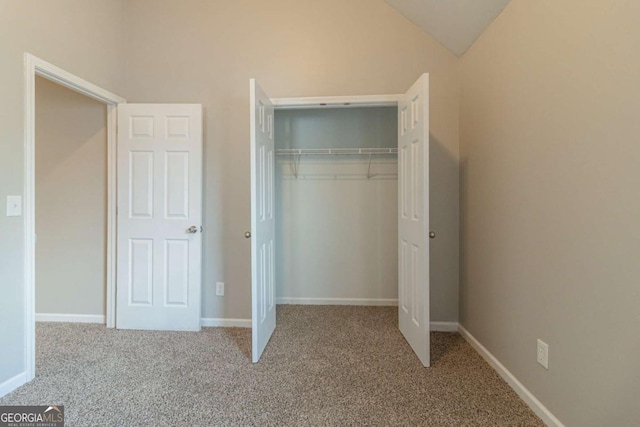 unfurnished bedroom with light carpet, vaulted ceiling, and a closet