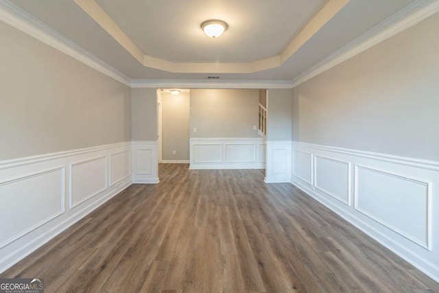 unfurnished room featuring dark hardwood / wood-style flooring, a tray ceiling, and crown molding