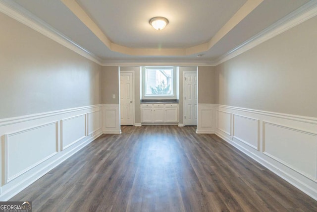 unfurnished room featuring a raised ceiling, dark hardwood / wood-style flooring, and crown molding