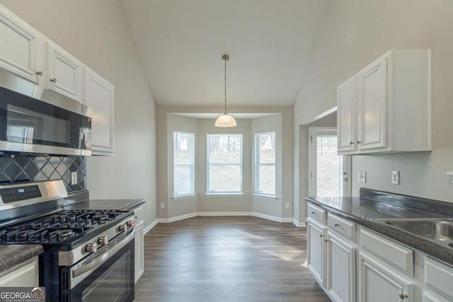 kitchen featuring dark hardwood / wood-style flooring, stainless steel appliances, vaulted ceiling, decorative light fixtures, and white cabinetry