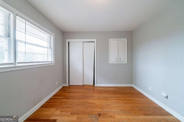 unfurnished bedroom with light wood-type flooring and a closet