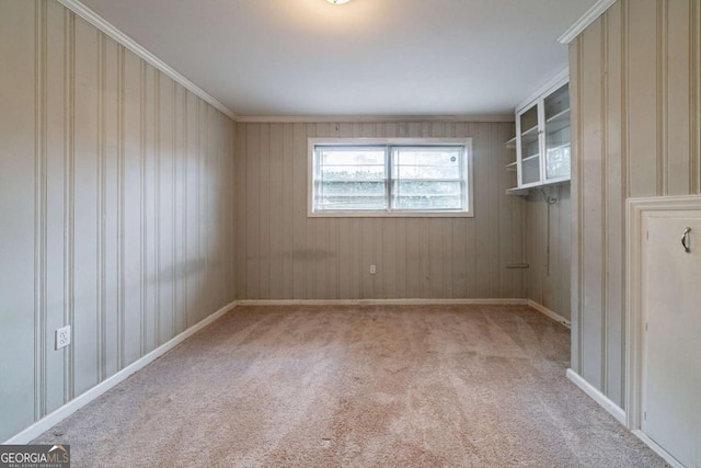 unfurnished room featuring light colored carpet, ornamental molding, and wooden walls