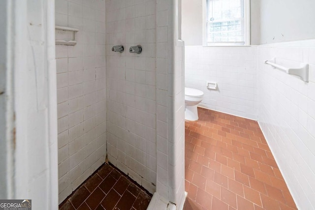 bathroom with toilet and tile walls