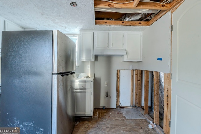 kitchen featuring stainless steel fridge, white cabinetry, and a textured ceiling