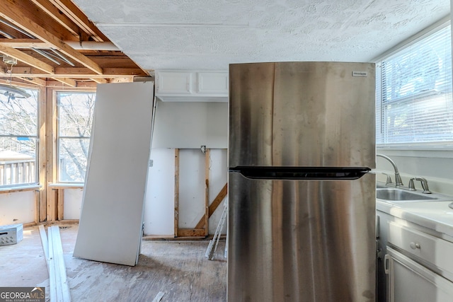 kitchen with white cabinets, stainless steel fridge, and sink