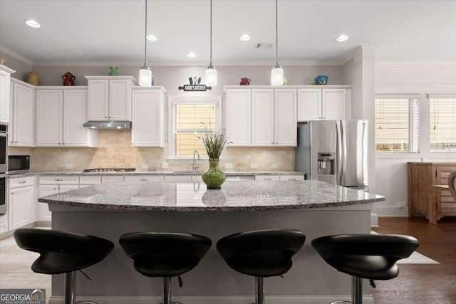 kitchen with appliances with stainless steel finishes, a center island, white cabinetry, and pendant lighting