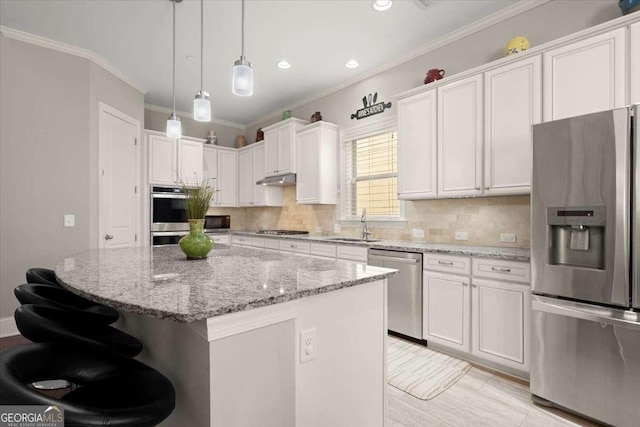 kitchen with light stone countertops, appliances with stainless steel finishes, decorative light fixtures, a kitchen island, and white cabinetry