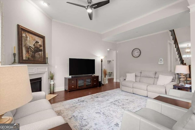 living room with dark hardwood / wood-style floors, ceiling fan, and ornamental molding