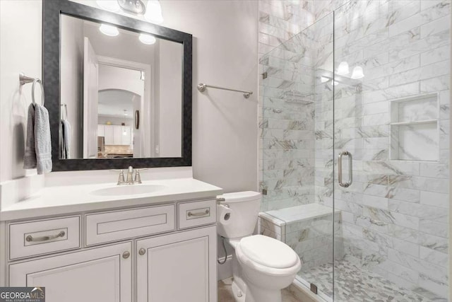 bathroom featuring vanity, toilet, and a shower with door