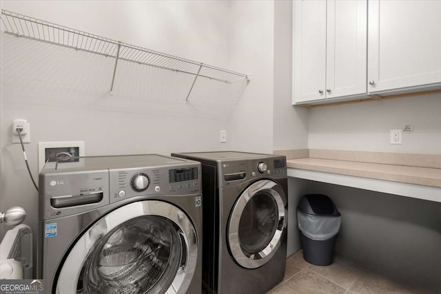 laundry room with cabinets, light tile patterned flooring, and washing machine and clothes dryer