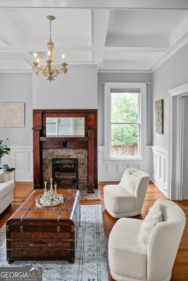 living room featuring beam ceiling, coffered ceiling, a stone fireplace, hardwood / wood-style floors, and a chandelier