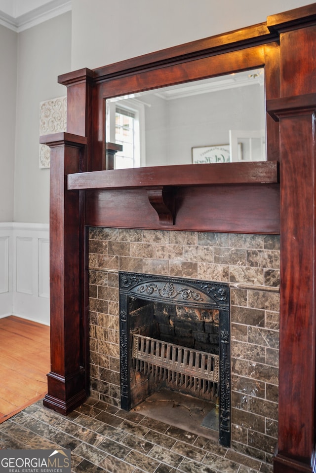 interior details featuring wood-type flooring, crown molding, and a tiled fireplace