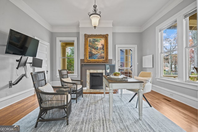 sitting room featuring a wealth of natural light, hardwood / wood-style floors, a high end fireplace, and crown molding