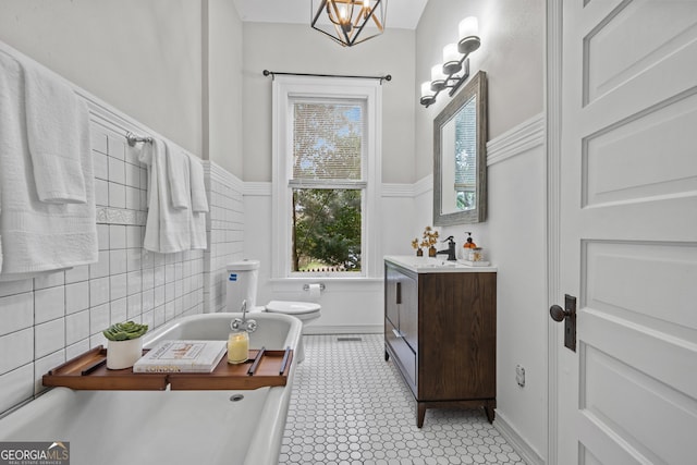 bathroom featuring vanity, a bathtub, toilet, tile walls, and a chandelier