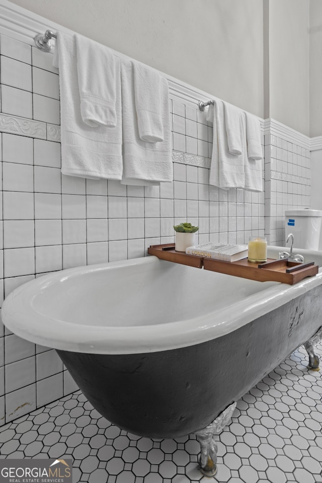 bathroom featuring tile patterned flooring, a bath, and tile walls