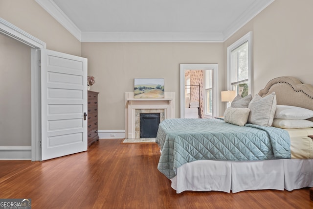 bedroom featuring hardwood / wood-style floors, crown molding, and a fireplace