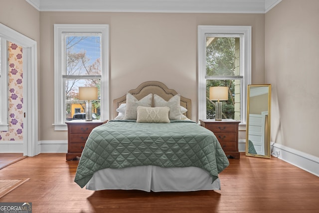 bedroom featuring hardwood / wood-style floors, multiple windows, and ornamental molding