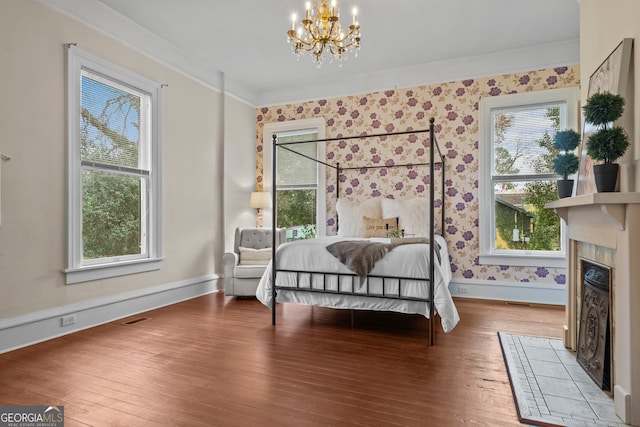 bedroom featuring hardwood / wood-style floors, a chandelier, a fireplace, and multiple windows