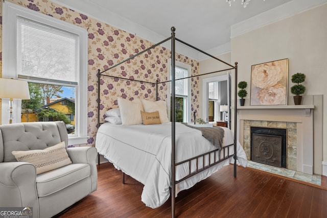 bedroom with dark hardwood / wood-style flooring, multiple windows, ornamental molding, and a tiled fireplace