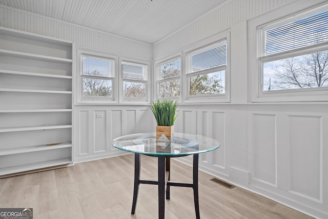 dining room with built in shelves and light hardwood / wood-style flooring